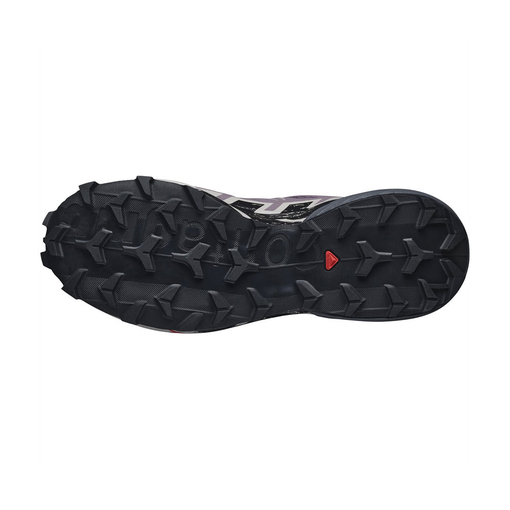 Sole of a Salomon trail running shoe with deep, multi-directional tread for mud evacuation and a red logo on a black background.