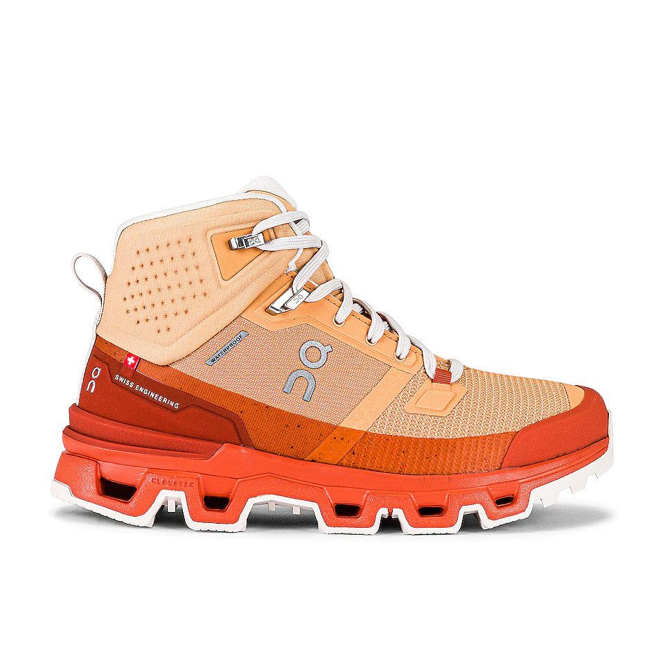 A modern, high-top hiking boot with orange and beige panels, featuring advanced cushioning with Helion superfoam and a rugged sole from On Running's ON RUNNING CLOUDROCK WATERPROOF COPPER/FLARE - WOMENS.