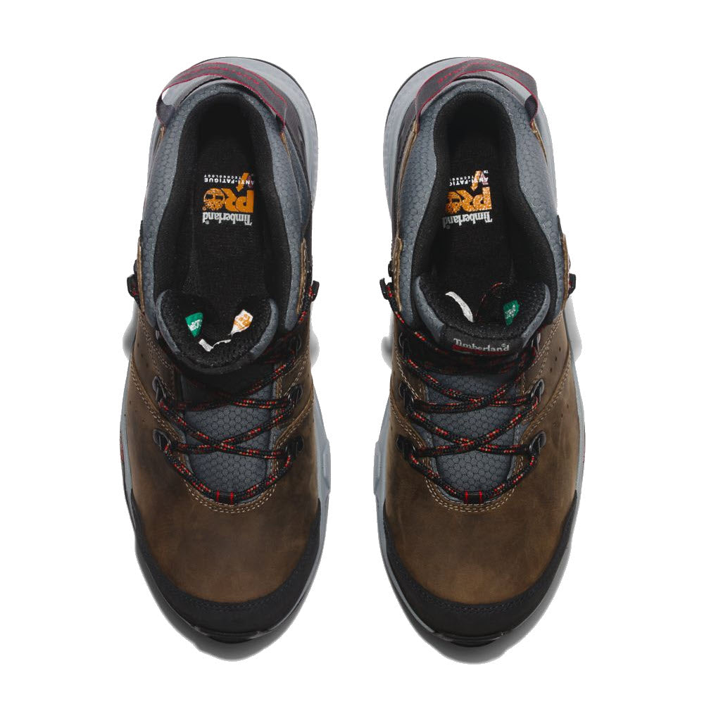 Top view of a pair of brown waterproof Timberland hiking boots with black laces, featuring logos on the Anti-Fatigue Technology footbed.