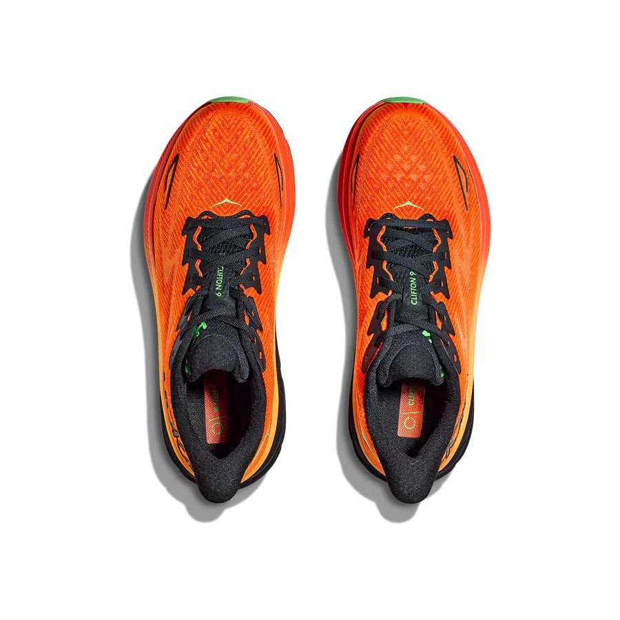 A pair of bright orange Hoka Clifton 9 running shoes with black laces and detailing, viewed from above on a white background.