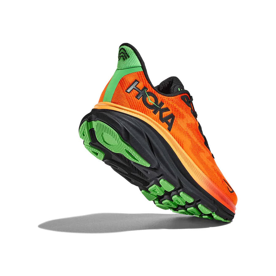 A vibrant orange and green Hoka Clifton 9 Flame/Vibrant Orange running shoe in profile view, featuring a prominent sole with an improved outsole design and the brand name on the side.