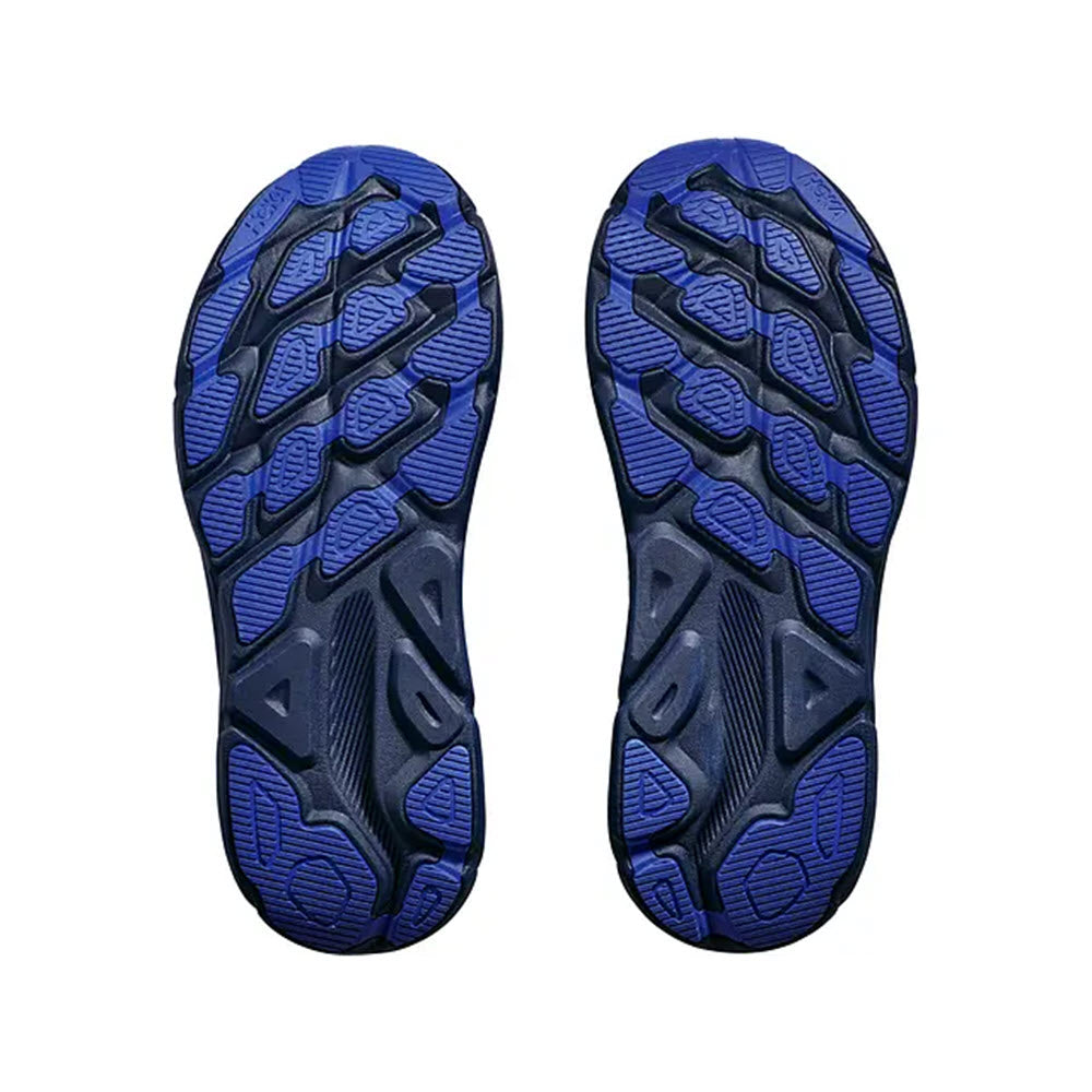 Pair of blue and black Hoka Gore-Tex hiking boot soles isolated on a white background, showing intricate tread patterns.