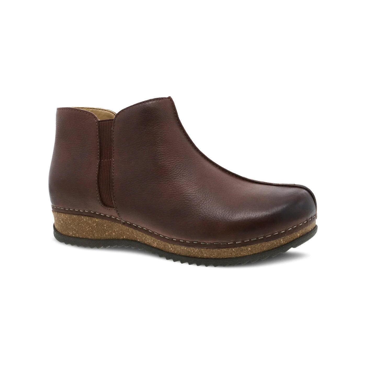 A single Dansko Makara bootie crafted from brown waxy leather with elastic side panels and a low, flat rubber sole, isolated on a white background.