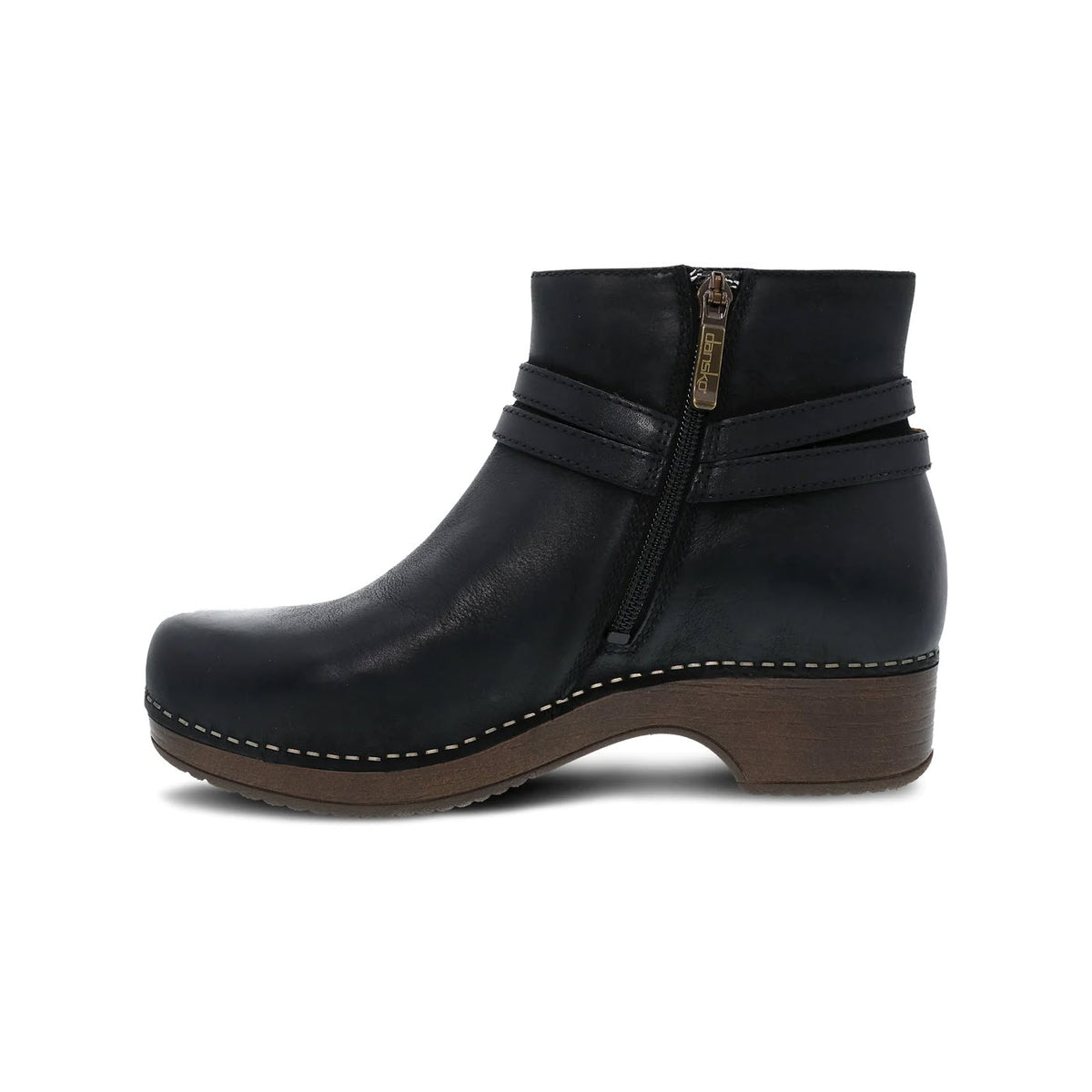 Dansko black leather ankle bootie with a side zipper and a wooden block heel, featuring patented stapled construction, isolated on a white background.