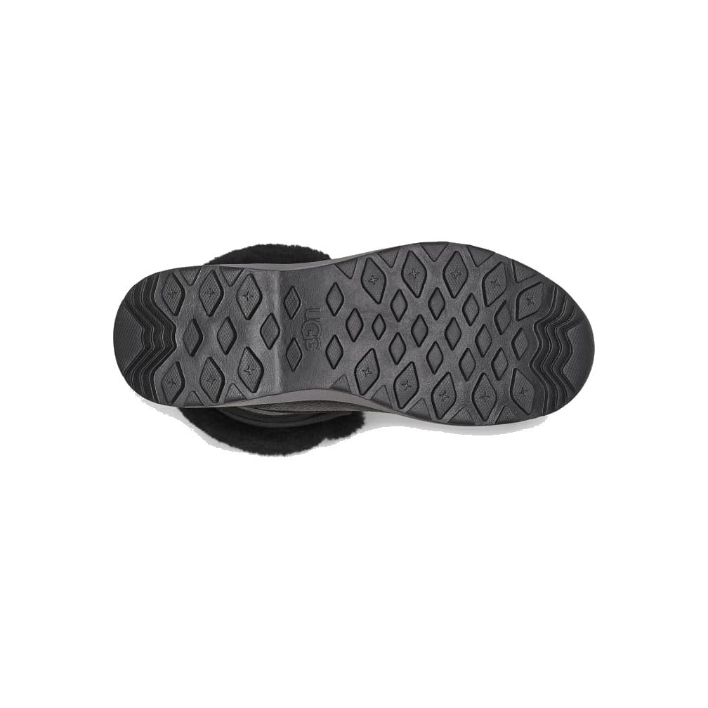 Black UGG sandal with adjustable straps, featuring a high-tech tread patterned sole, isolated on a white background.