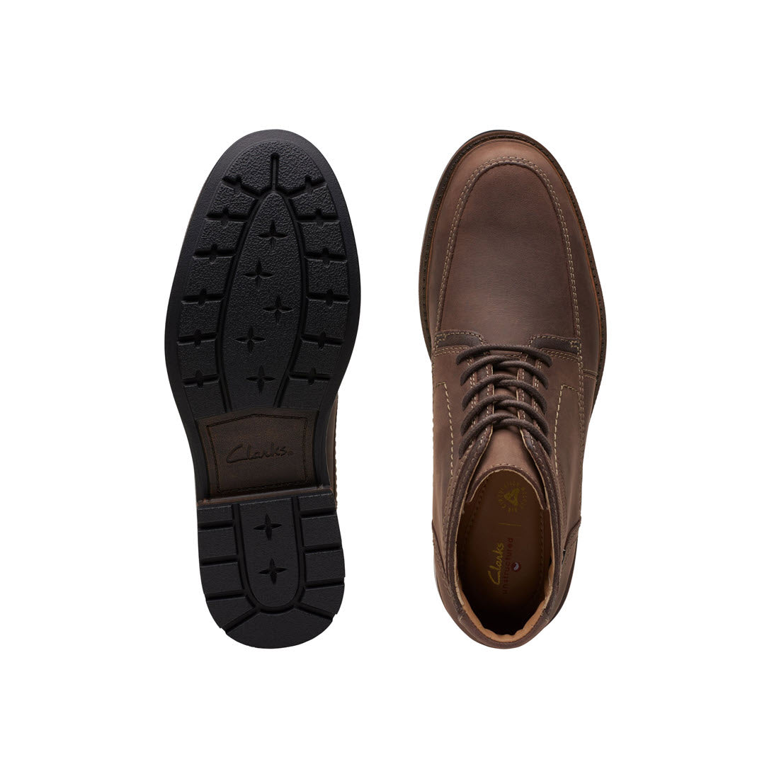 A pair of Clark&#39;s Unshire Hi WP Dark Brown Leather shoes, designed with smart-casual aesthetics, displayed top down, with one shoe flipped to show the sole.