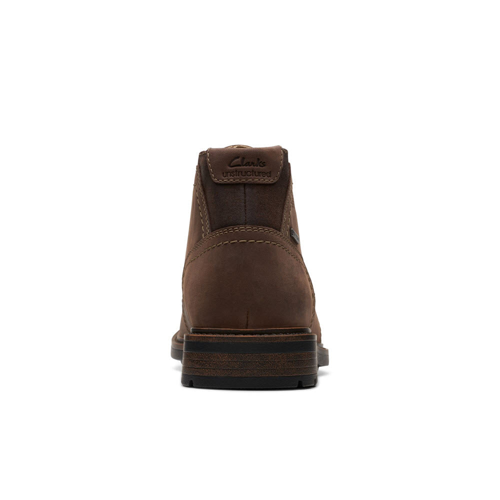 Sentence with the replaced product: Rear view of a single brown Clarks Unshire Hi WP Dark Brown Leather shoe against a white background.