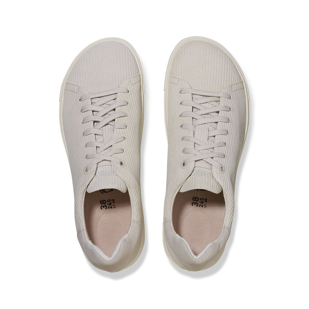 A pair of Birkenstock beige sneakers with white laces viewed from above, placed side by side on a white background, featuring a contoured footbed.