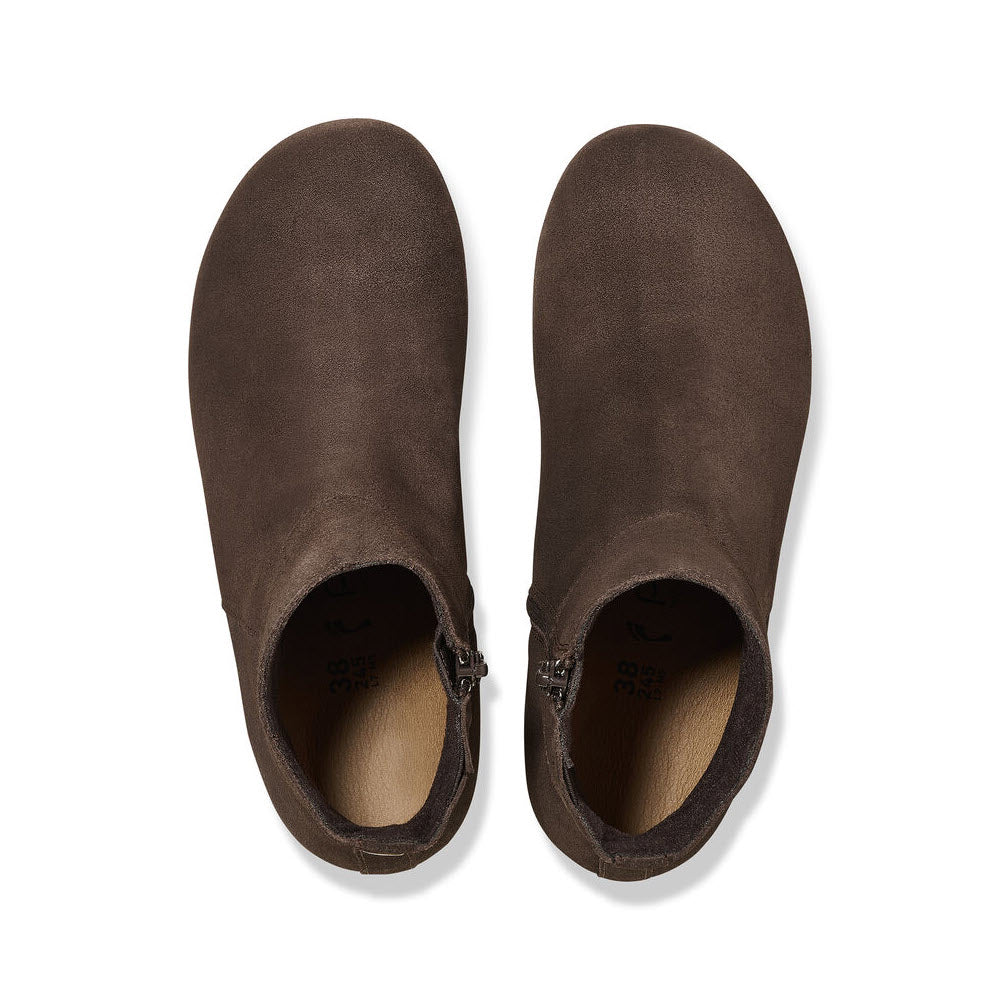 A pair of brown suede clogs with a Birkenstock footbed, viewed from above, showing the inner lining and brand labels.