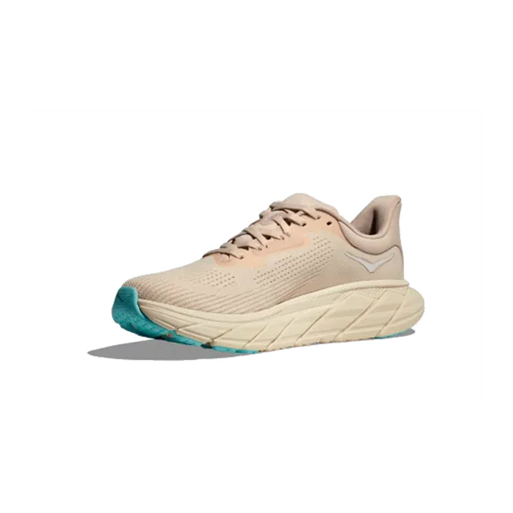 Side view of a light tan Hoka Arahi 7 stability shoe with a turquoise sole and white detailing on a white background.