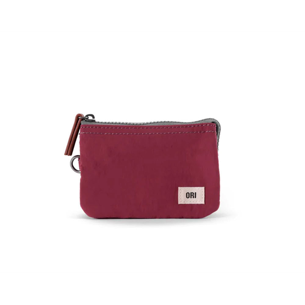 A small, burgundy-colored ORI LONDON CARNABY SMALL POUCH PLUM with a zipper and a branded tag labeled "ori" on a white background.