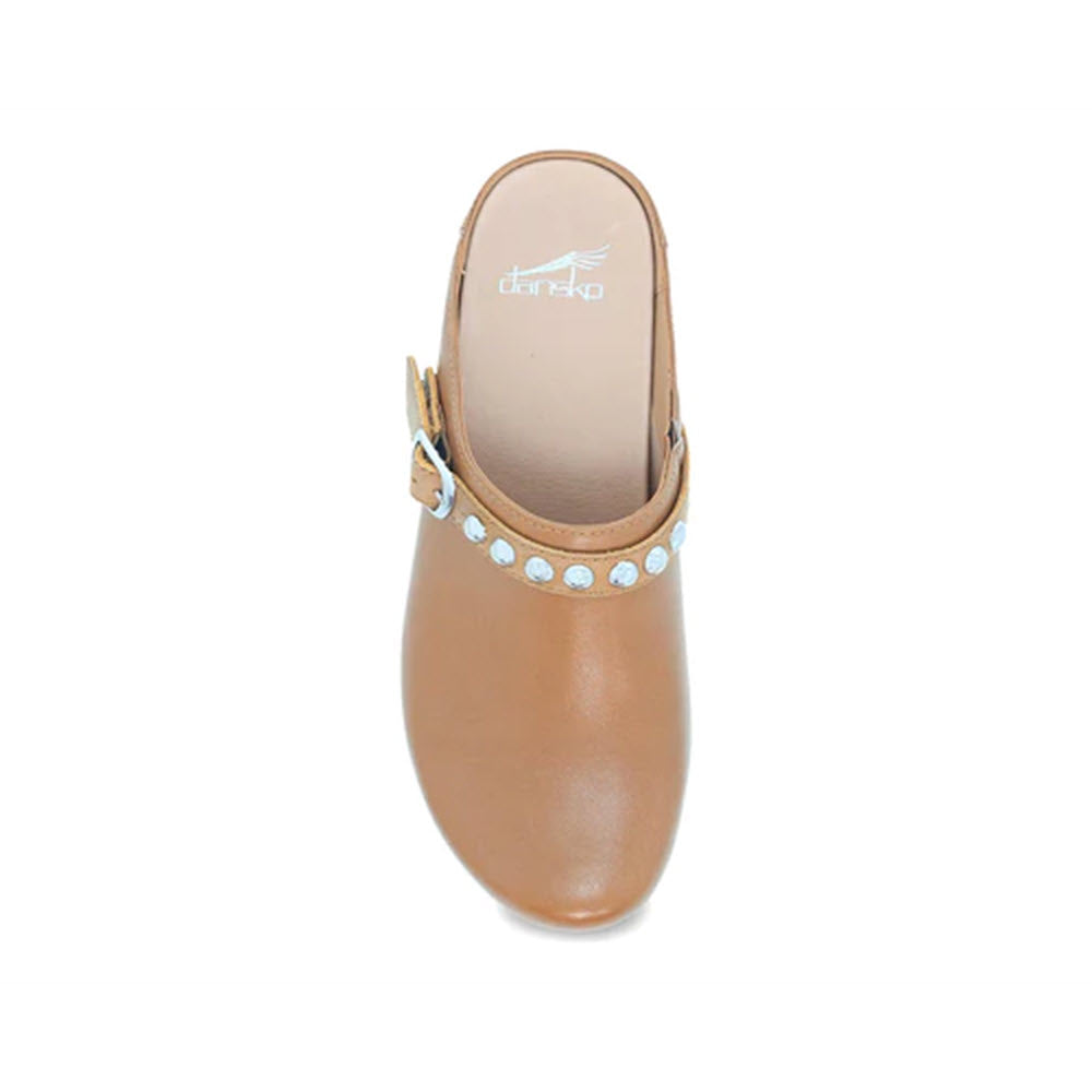 Top view of a Dansko Brittton tan mary jane shoe with silver hardware along the strap on a white background.