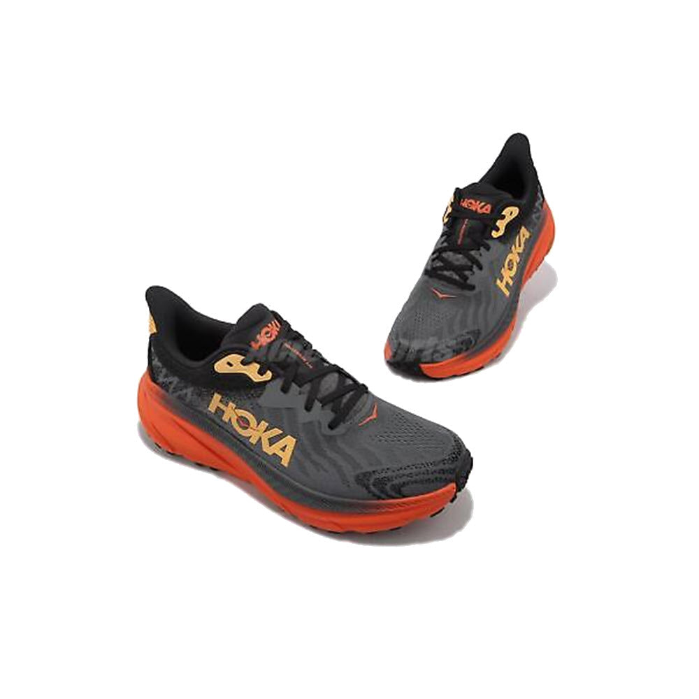 A pair of HOKA CHALLENGER ATR 7 CASTLEROCK/FLAME trail running shoes in black and orange, displayed on a white background.