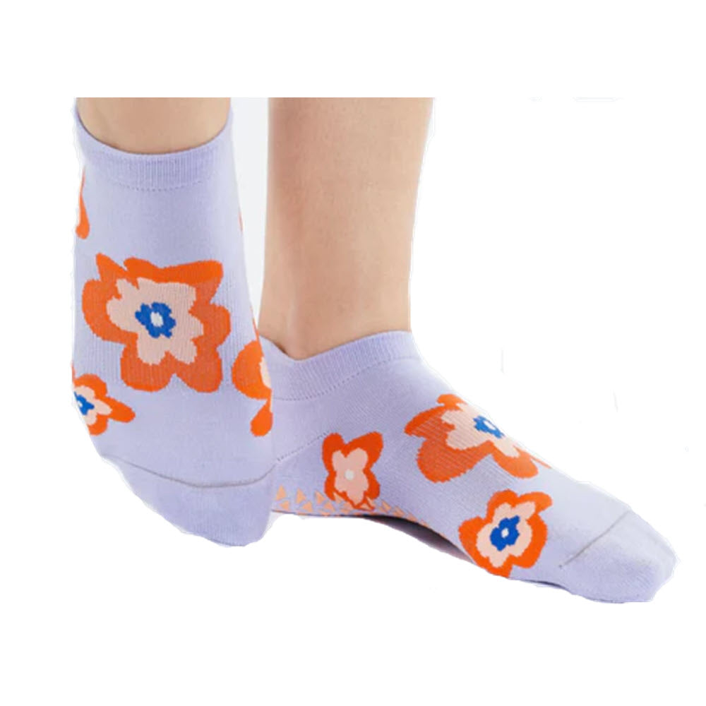 A person wearing POINTE STUDIO POSIE LOW GRIP SOCKS LAVENDER adorned with orange and white floral patterns, photographed against a white background.