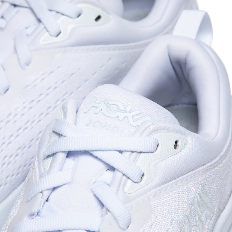 Close-up of a white Hoka Bondi 8 running shoe focusing on its laces and padded tongue with brand imprint.